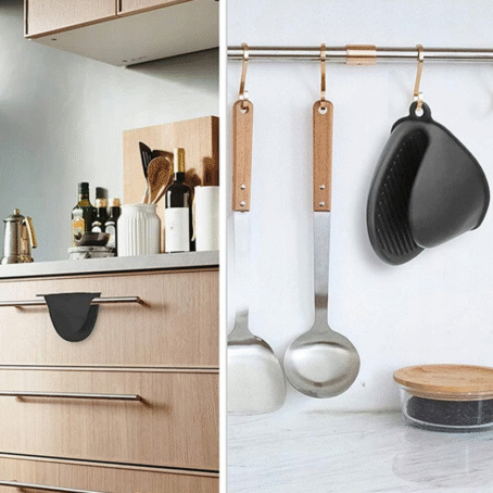 Black silicone oven mitt hanging on a kitchen rail next to utensils and also placed on a drawer handle in a modern kitchen.