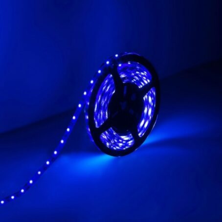 Blue LED strip rolled on a reel, glowing with intense light in the dark.